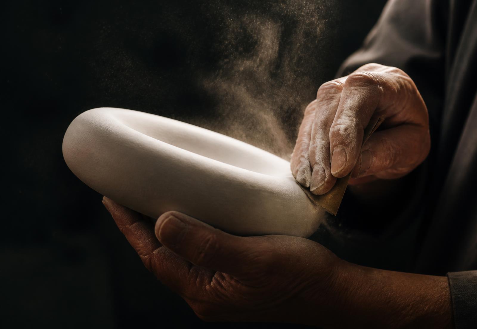 Hands finishing a pigmented cast form in the studio