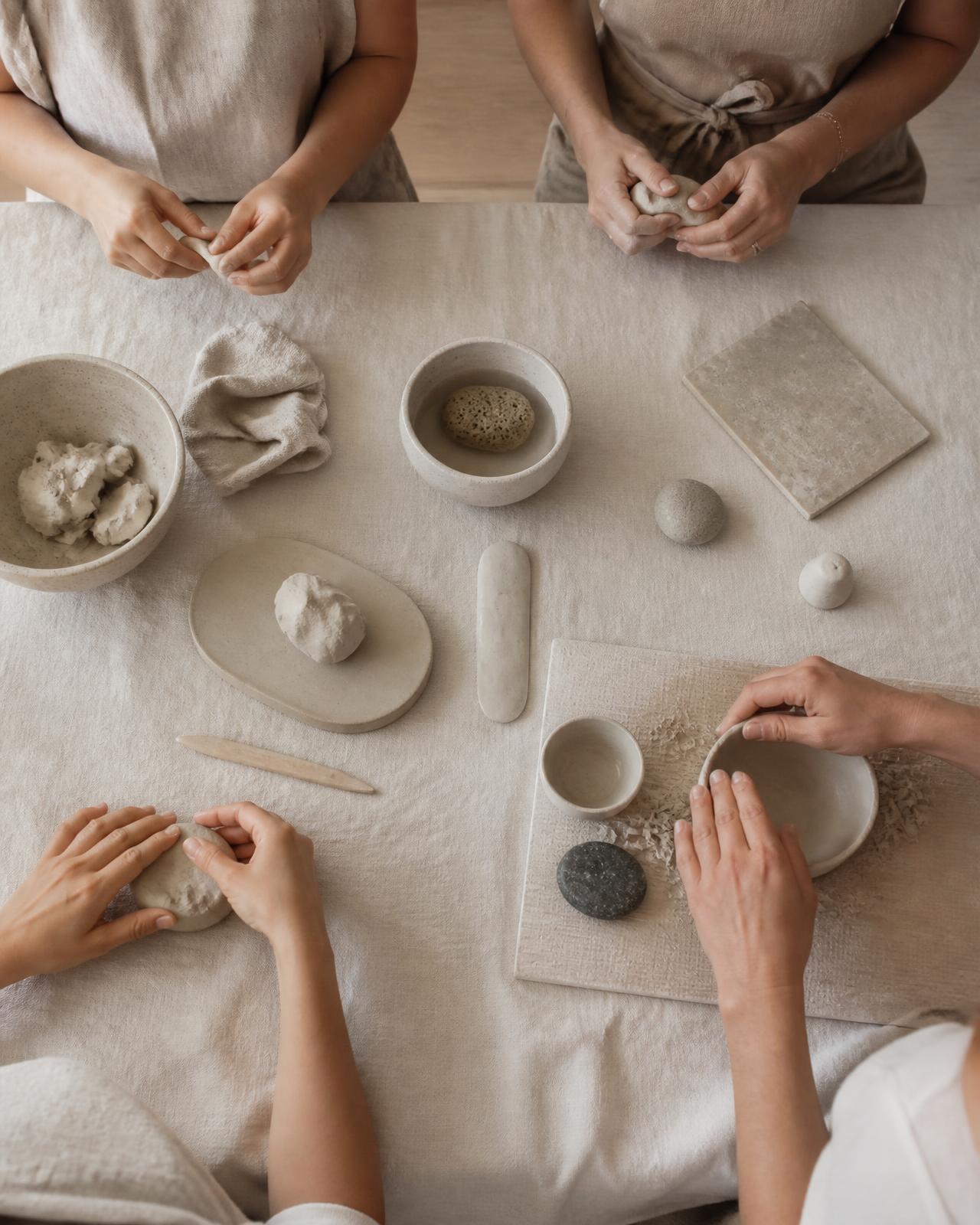 A calm table setting with hands shaping pale material in soft daylight
